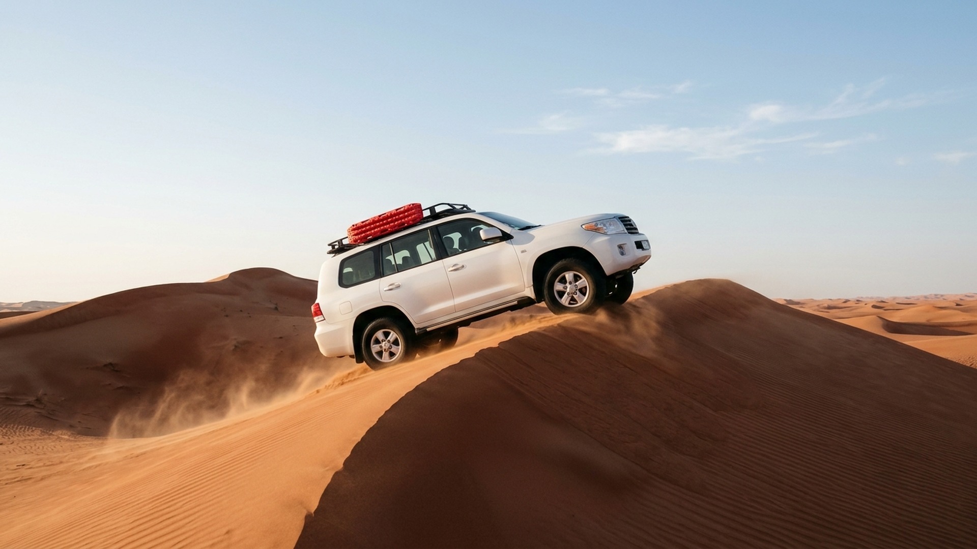 4WD SUV cresting a red sand dune on morning desert safari in Dubai