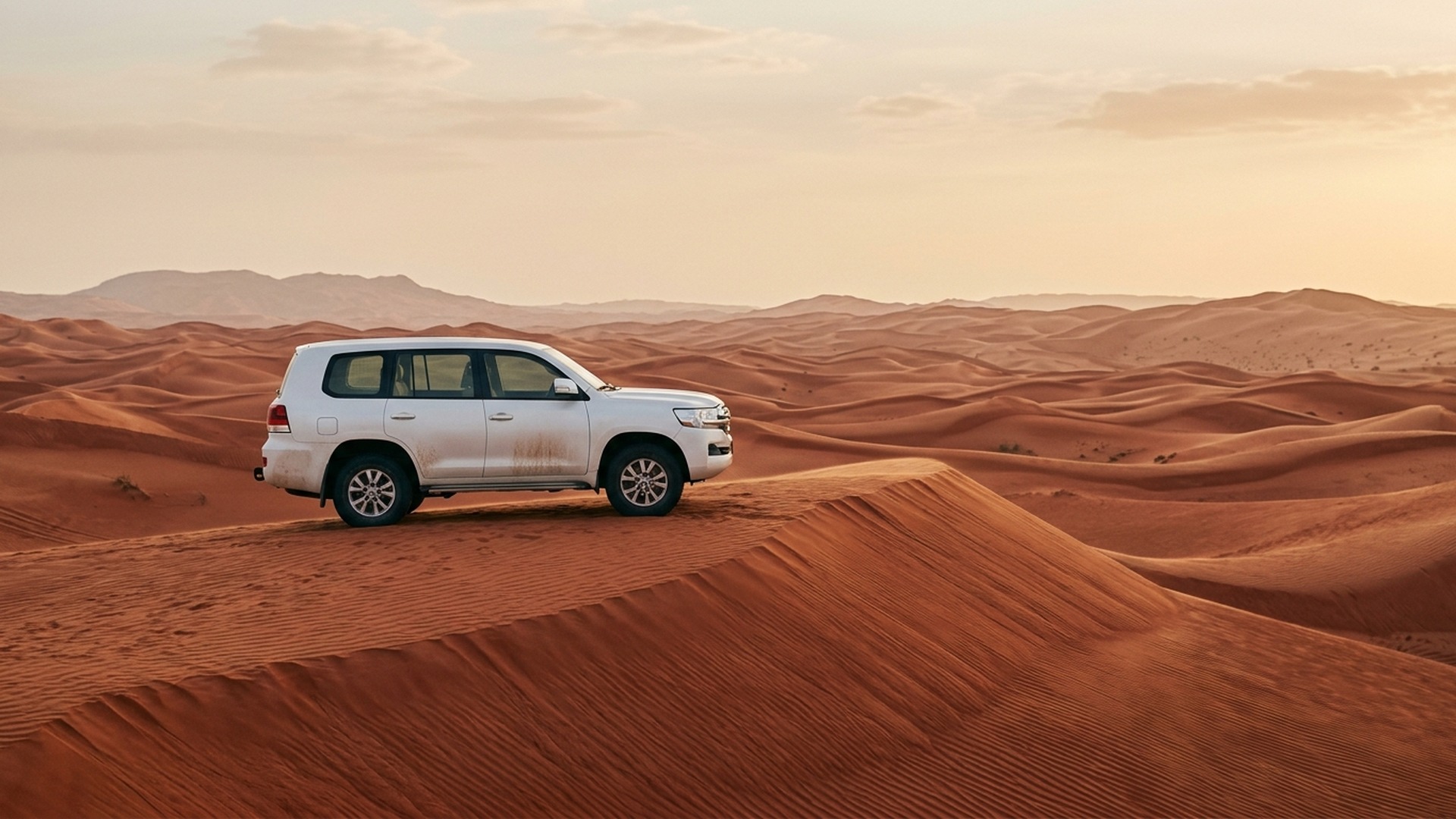Private 4WD alone on a red sand crest in Lahbab at sunrise